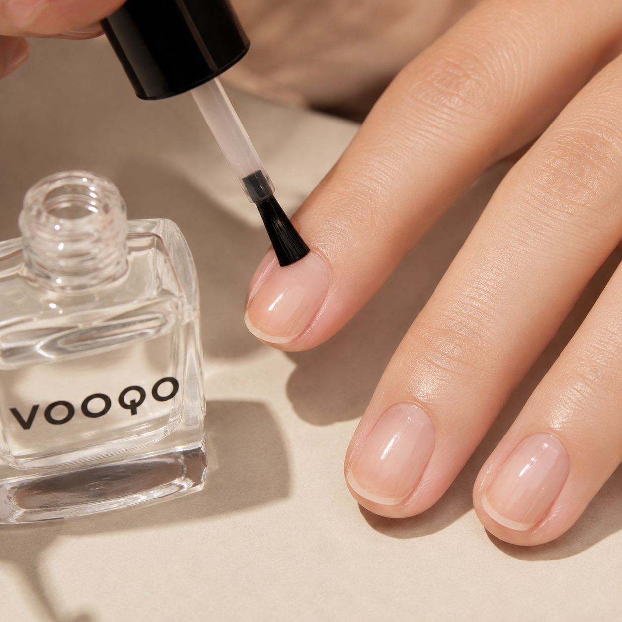 Close-up of Vooqo Nail Base Coat being applied in a thin layer to a clean bare nail