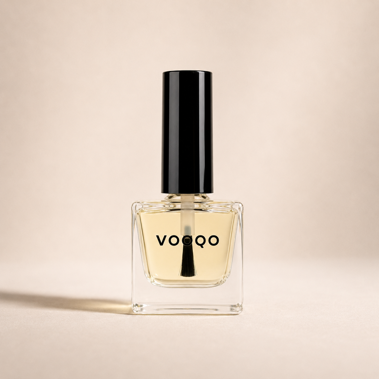 Vooqo Nail Treatment with pale golden botanical oil in a clear glass bottle on a warm ivory background